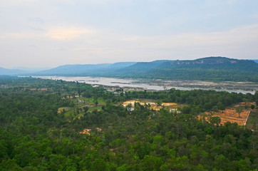 Fototapeta na wymiar Wide river in green tropical forest and range in Asia