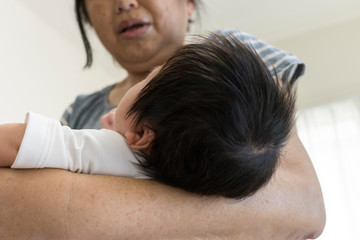 Obraz na płótnie Canvas 新生児の首を支える60代の女性の腕