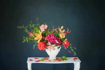 bouquet of summer flowers in vase on vintage white wooden shelf on dark background