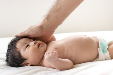 Fototapeta na wymiar 赤ちゃんの頭を撫でる男性の手