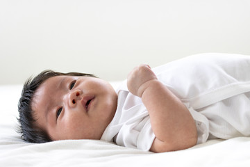 Obraz na płótnie Canvas シーツで横になって悲しい顔をする赤ちゃん