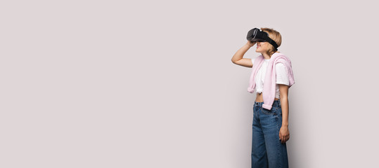 Side view photo of a blonde lady using vr headset and posing on a white studio wall
