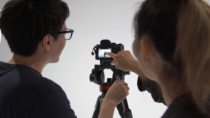 撮った動画を確認する映像カメラマンと被写体の女性