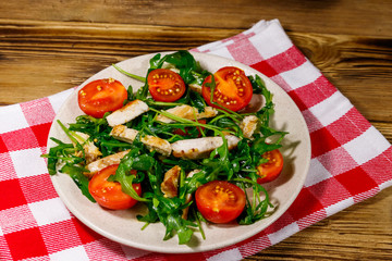 Tasty salad of fried chicken breast, fresh arugula and cherry tomatoes on wooden table