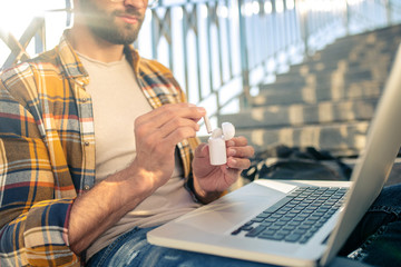 Man with laptop on stairs holding wireless headphones