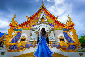 Asian female tourist wearing a blue dress visits Khuakrae Temple in Chiang Rai, Thailand. - obrazy, fototapety, plakaty