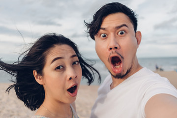 Funny wow face selfie of couple on windy beach.