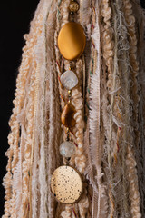 Borla colgante cortina color crudo de cintas de hilo de lana y piedras y joyas con fondo negro