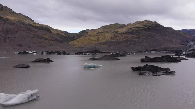 Aerial images flying over a glacial lagoon full of icebergs. Passing very close to the icebergs.
