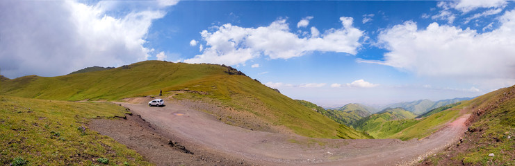 Beautiful panoramic view of green mountains with dangerous gravel road. Ketmen or Ketpen mountains gorge and mountain pass. Tourism in Kazakhstan.