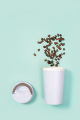 Reusable eco coffee cup with roasted coffee beans.