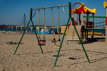 Children swing on the sandy beach.