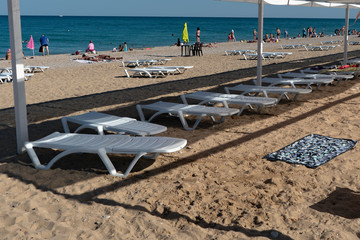 White sun loungers on the rocky beach.