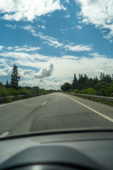 Vista desde el coche de una carretera con el cielo lleno de nubes