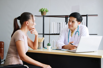 Young Asian male psychiatrist is specialist in psychiatry Caucasain female Patient is smiling together for therapy and talking for encourage with laptop in Clinical treatment for emotional symptoms.
