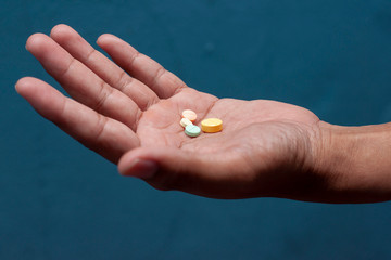 Medicine pills of various sizes in the hands of the patient.