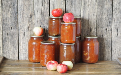 Autumn preparations of homemade apple jam for future use. Jam in a glass vase on the background of a wooden table with apples.