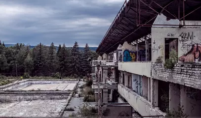 Foto op Plexiglas Abandoned destroyed building against the background of the forest. Abandonment on light background. Old grunge background. Architecture concept. Building architecture exterior. Stone wall background © Denis