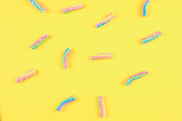 Rainbow jelly candies on a yellow background.