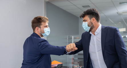 Two businessmen shaking hands with their elbows due to precautionary measures