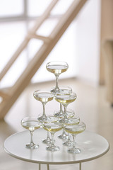 Tower made of glasses with champagne on table in room