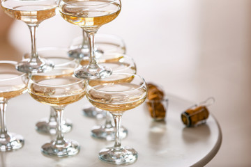 Tower made of glasses with champagne on table in room