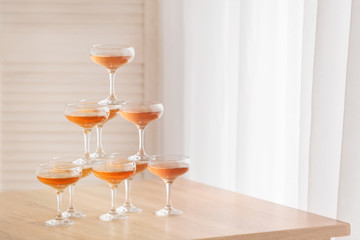 Tower made of glasses with champagne on table in room