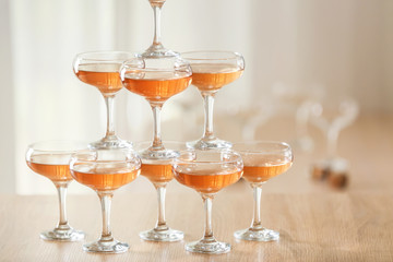 Tower made of glasses with champagne on table indoors