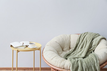 Soft armchair and table near light wall in room