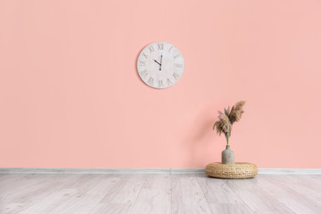 Clock and vase with floral decor in empty room