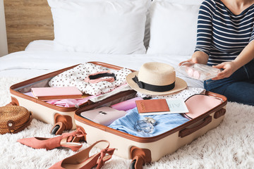 Woman packing suitcase for journey at home