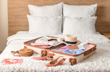 Suitcase with travel accessories on bed