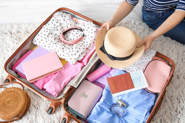 Woman packing suitcase for journey at home