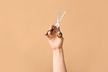 Female hand hairdresser's scissors on color background