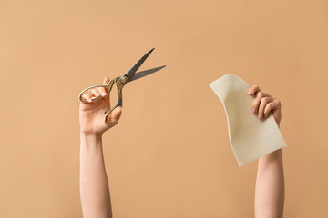 Female hands tailor's scissors and fabric on color background