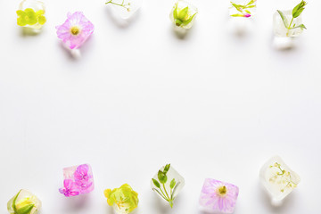 Frozen flowers in ice on white background