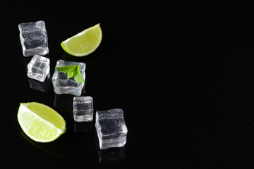 Ice cubes, lime and mint on dark background