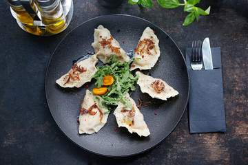 Dumplings with meat. Traditional homemade meat dumplings served on a black plate. Suggestion to serve the dish. Top view.