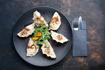 Dumplings with meat. Traditional homemade meat dumplings served on a black plate. Suggestion to serve the dish. Top view.