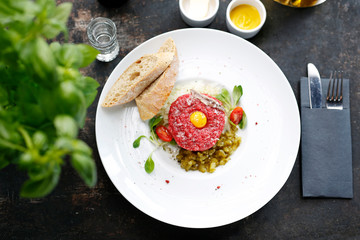 Chopped beef, steak tartare served with yolk and pickles. Appetizing appetizer. Suggestion to serve the dish. Culinary photography.