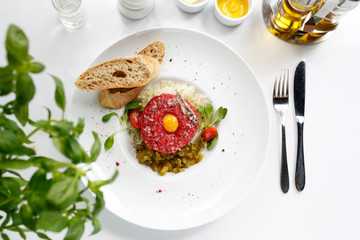 Chopped beef, steak tartare served with yolk and pickles. Appetizing appetizer. Suggestion to serve the dish. Culinary photography.