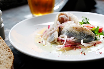 Herring in oil with onion and fresh vegetable salad.
Appetizing appetizer. Suggestion to serve the dish. Culinary photography.