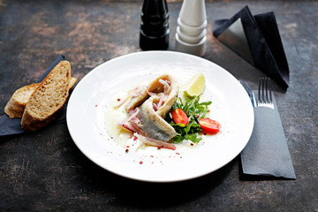 Herring in oil with onion and fresh vegetable salad.
Appetizing appetizer. Suggestion to serve the dish. Culinary photography.