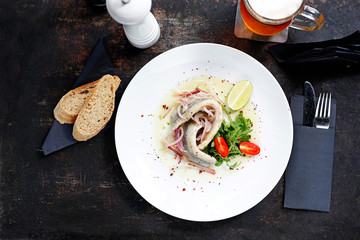 Herring in oil with onion and fresh vegetable salad.
Appetizing appetizer. Suggestion to serve the dish. Culinary photography.