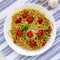 Homemade Pesto Pasta with Tomatoes and Pine Nuts on a white plate, view from above. Flat lay, overhead, from above.