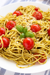 Homemade Pesto Pasta with Tomatoes and Pine Nuts on a white plate, side view. Close-up.