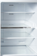 Clean empty shelves in white refrigerator. Empty open fridge with shelves, refrigerator. shelves in empty open white fridge background