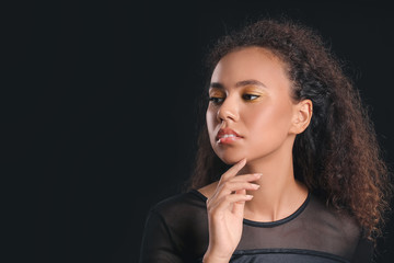 Fototapeta na wymiar Young African-American woman with beautiful eyeshadows on dark background
