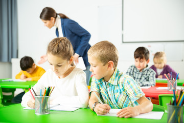 Fototapeta premium Happy pupils chattering sitting at lesson in elementary school. High quality photo