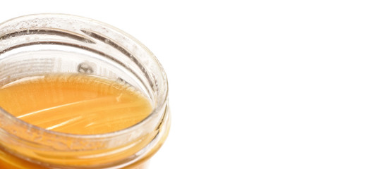 Glass jar with amber coloured honey, closeup detail, isolated on white background, space for text right side